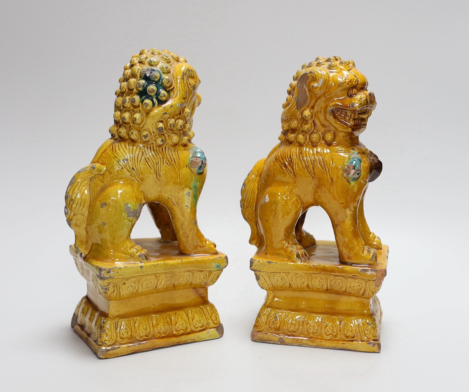 A pair of Chinese ochre glazed Buddhist lion figures, 25cm